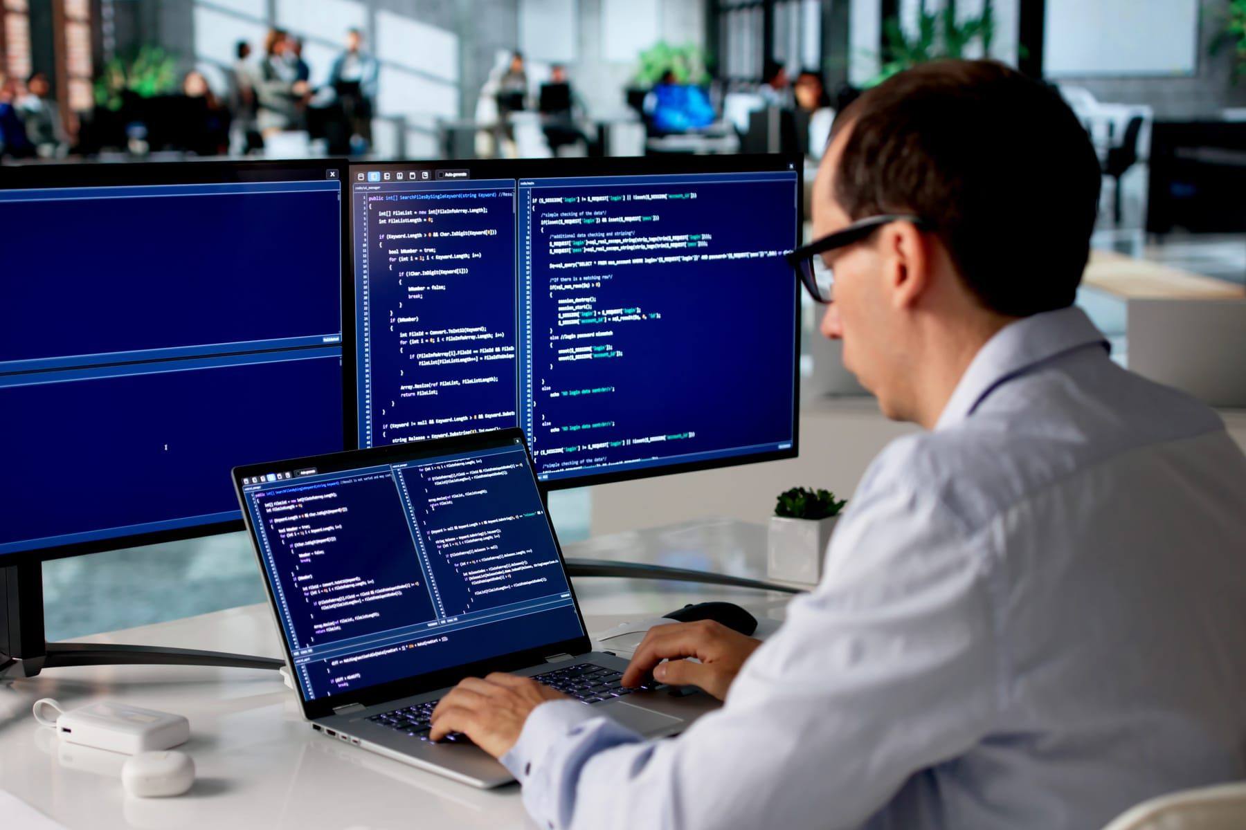 Softwareentwickler an einem Arbeitsplatz mit mehreren Bildschirmen