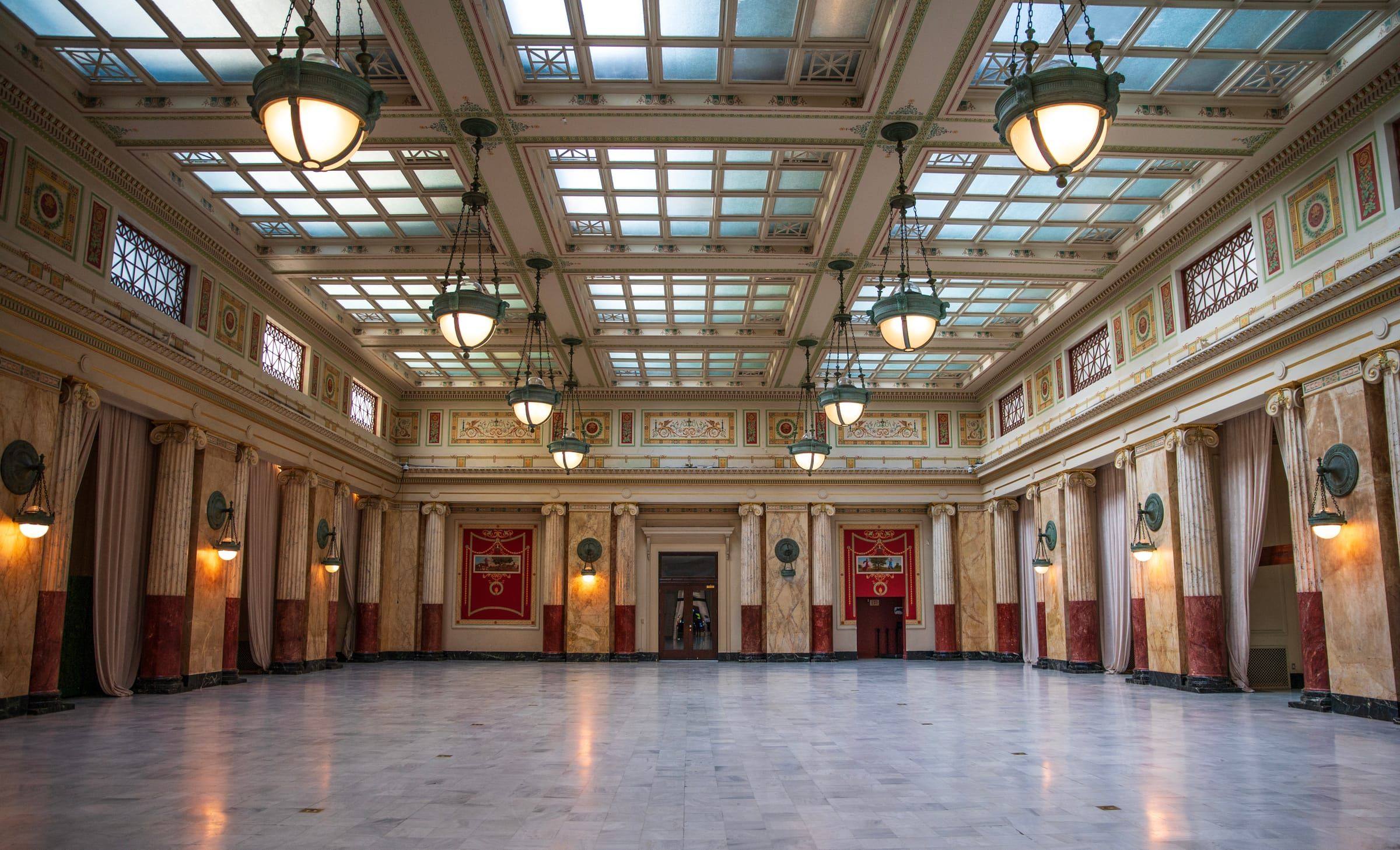Historic grand hall with marble columns and a coffered ceiling