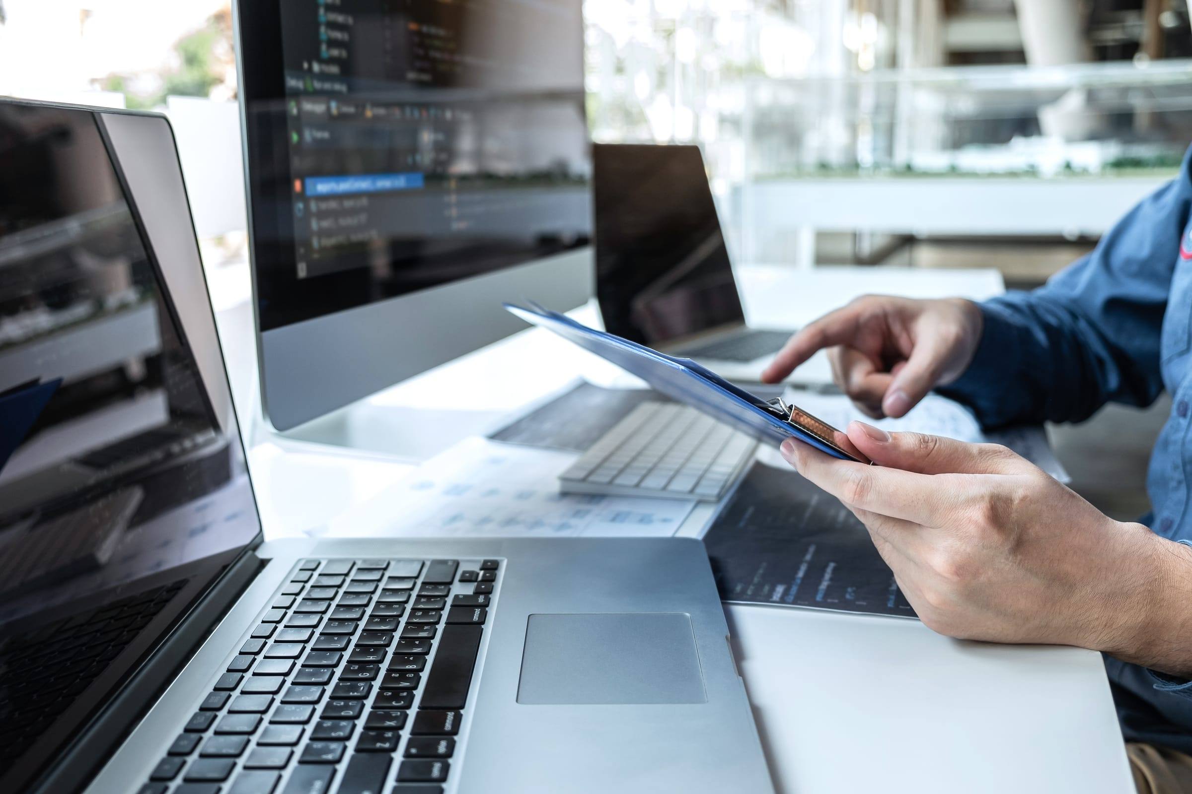 Developer at a workstation with a laptop and a code editor on the monitor