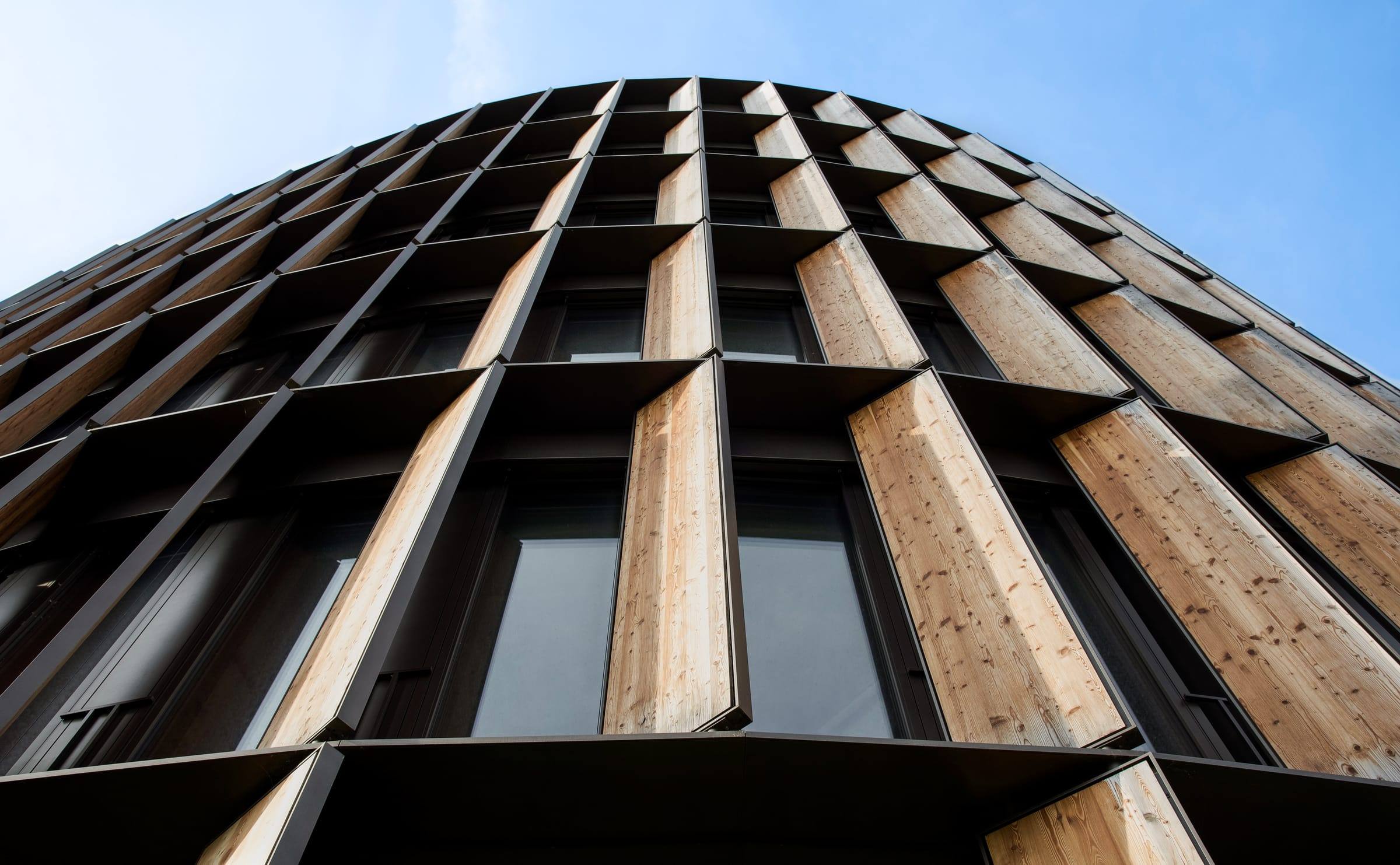 Untersicht einer geschwungenen Holz-Lamellenfassade an einem modernen Gebäude