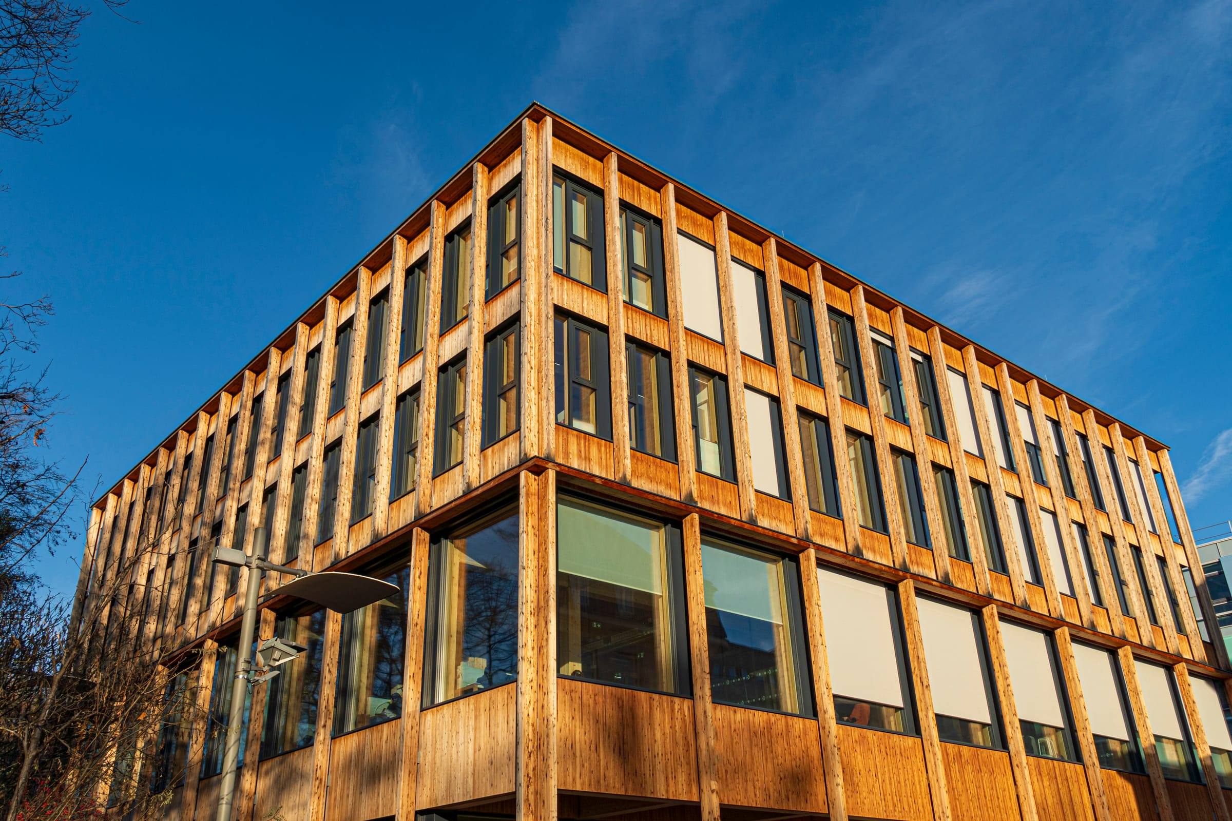 Modernes Bürogebäude aus Holz mit großen Fenstern bei Sonnenuntergang